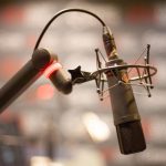 Studio microphone setup, professional recording equipment for podcasting or broadcasting, high-quality mic with shock mount and pop filter.